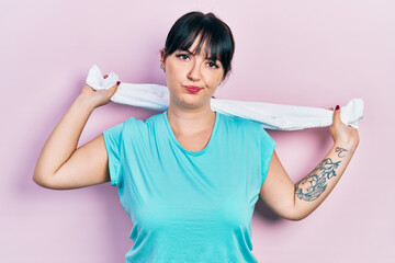 Canvas Print - Young hispanic woman wearing sportswear holding towel skeptic and nervous, frowning upset because of problem. negative person.