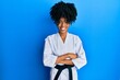 © Krakenimages.com - African american woman with afro hair wearing karate kimono and black belt happy face smiling with crossed arms looking at the camera. positive person.