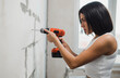 © kalinichenkod - beautiful girl in overalls with electric drill