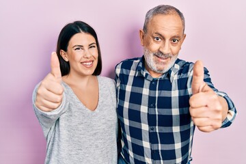 Canvas Print - Hispanic father and daughter wearing casual clothes approving doing positive gesture with hand, thumbs up smiling and happy for success. winner gesture.