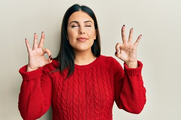 Poster - Beautiful brunette woman wearing wool winter sweater relax and smiling with eyes closed doing meditation gesture with fingers. yoga concept.