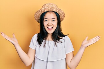 Wall Mural - Young chinese girl wearing summer hat celebrating victory with happy smile and winner expression with raised hands