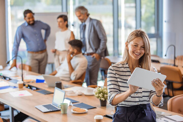 Wall Mural - Beautiful business woman holding tablet computer in office. Portrait of happy businesswoman using digital tablet in agency. Successful business woman in casual clothing working on tablet.