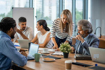 Wall Mural - Young designer giving some new ideas about project to his partners in conference room. Business people discussing over new business project in office. Business People Working in The Office