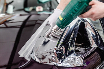 Wall Mural - Car wrapping specialist putting silver mirror chrome foil on car. Selective focus.