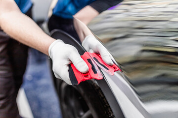 Wall Mural - Car wrapping specialist putting silver mirror chrome foil on car. Selective focus.