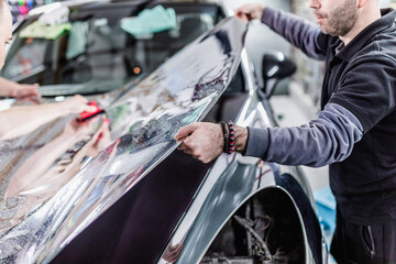 Wall Mural - Car wrapping specialist putting silver mirror chrome foil on car. Selective focus.