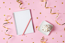 New Year, Christmas Or Holiday Wish List Concept. Notepad, Golden Tinsel, And A Cup Of Hot Chocolate With Marshmallows Isolated On Pink Background. Holiday Banner With Copy Space.