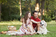 © Seventyfour - Full length portrait of young couple with dog enjoying picnic outdoors on green grass, copy space
