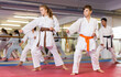 © JackF - Teenager children wearing karate uniform fighters poses in white kimono during group training in gym