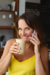 © ksenija1803z - portrait of smiling woman with cup of coffee in her hand and talking o smartphone