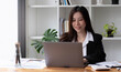 © wichayada - Business asian woman using laptop for do math finance on wooden desk in office, tax, accounting, financial concept