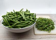 Raw Green Beans In A White Bowl On Wooden Table With Scraps On The Side