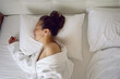 © saulich84 - woman in white robe is lying on the bed and sleeping near window in hotel apartment after a shower