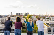 © Westend61 - Coworkers looking at cityscape while standing on rooftop
