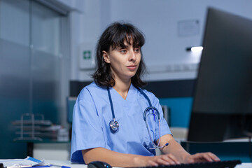 Wall Mural - Healthcare specialist working with monitor and keyboard in doctors office. Medical assistant using computer with technology for professional support and assistance, working late.