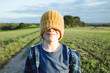 © Westend61 - Smiling boy with eyes covered by knit hat on field