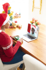 Poster - African american woman in santa hat making laptop christmas video call with smiling boy in santa hat