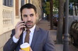 Mistrustful looking businessman answering phone call outdoors
