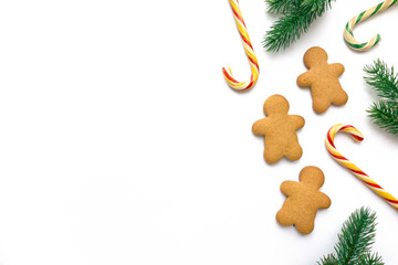 Christmas gingerbread cookies in the shape of man with lollipops and fir branches on white background, space for text