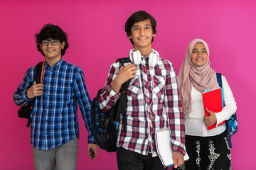 Wall Mural - A group of Arab teenagers, a student team walking forward into the future and back to school the concept of a pink background. The concept of successful education for young people. Selective focus