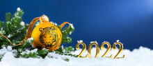 2022 Is Year Of The Tiger. Happy New Year Greeting Card. Symbol Of Year Lunar Chinese Calendar Tiger On Christmas Ball And Gold Numbers 2022 In Snow.