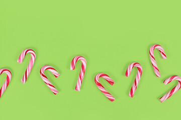 Sticker - Small red and white striped Christmas candy cane sweets in row on green background