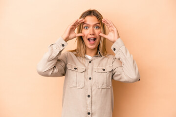 Wall Mural - Young caucasian woman isolated on beige background receiving a pleasant surprise, excited and raising hands.