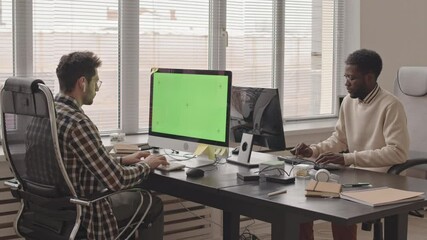 Wall Mural - stab shot with slowmo of two young multiethnic software engineers typing on keyboards looking at com