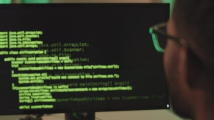 Wall Mural - close-up of african-american programmer looking at black computer screen with running program code