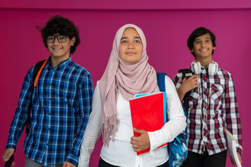 Wall Mural - A group of Arab teenagers, a student team walking forward into the future and back to school the concept of a pink background. The concept of successful education for young people. Selective focus