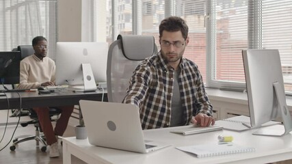 Wall Mural - stab shot of two young multi-ethnic male programmers working on pcs in contemporary office