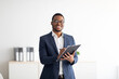 © Prostock-studio - Happy young black male psychologist writing in clipboard, looking at camera and smiling in modern office