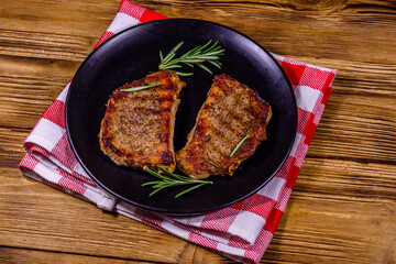 Wall Mural - Plate with roasted steaks and rosemary twigs on a wooden table