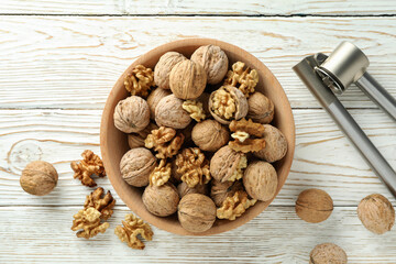 Wall Mural - Nutcracker and bowl of walnuts on white wooden background