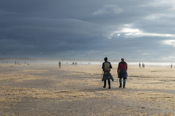 Wall Mural - Two men strolling on a seaweed covered beach