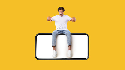 Wall Mural - man sitting on white empty smartphone screen and pointing down