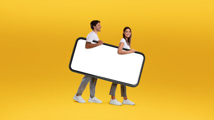 Wall Mural - Cheerful couple walking with big white empty smartphone screen