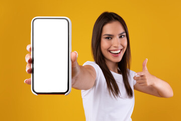 Wall Mural - Cheerful woman pointing at white empty smartphone screen