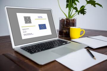 Laptop with covid vaccination certificate and qr code on screen