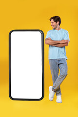 Wall Mural - Guy standing near big empty smartphone screen with crossed hands