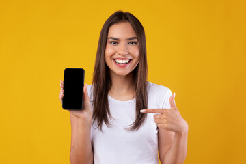 Wall Mural - Happy woman pointing at white empty smartphone screen