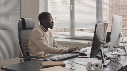 Wall Mural - stab shot of young african-american software developer working on pc sitting at desk by window in br