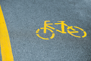 Yellow bicycle sign on sidewalk, road yellow marking for traffic safety near highway