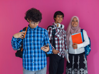 Wall Mural - A group of Arab teenagers, a student team walking forward into the future and back to school the concept of a pink background. The concept of successful education for young people. Selective focus