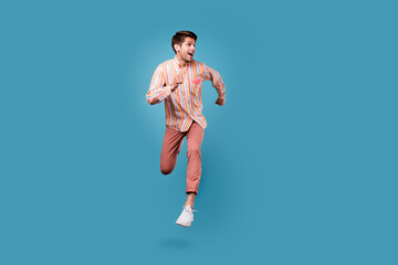 Full body photo of young man happy positive smile jump go walk run look empty space isolated over blue color background