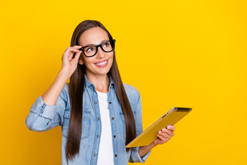 Sticker - Photo of young cheerful girl manager hold tablet look empty space minded isolated over yellow color background