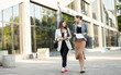 © splitov27 - Two business women friends communicate while walking in the city on the background of a business building
