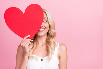 Wall Mural - Photo of shiny pretty young lady wear white overall smiling large red heart close eye looking empty space isolated pink color background