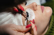 © fotofrol - Eyelash extension procedure. Master tweezers fake long lashes beautiful female eyes.